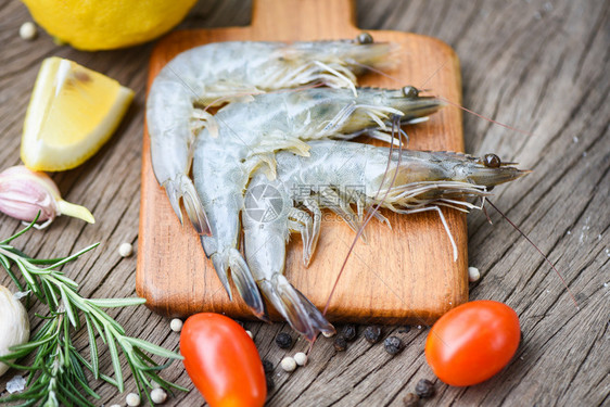 木制切板上新鲜虾配有食用海产品生虾的饲料草药和香
